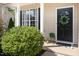 Inviting front porch with a wreath, lush greenery, and a stylish doormat at 103 Woolard Way, Apex, NC 27502