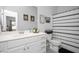Well-lit bathroom with a white vanity, framed decorative art, and black and white patterned shower curtain at 105 Smoky Emerald Way, Holly Springs, NC 27540