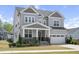 Charming two-story home features gray siding, stone accents, covered porch, and attached two-car garage at 105 Smoky Emerald Way, Holly Springs, NC 27540