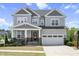 Charming two-story home featuring a well-manicured lawn and a two-car garage on a beautiful sunny day at 105 Smoky Emerald Way, Holly Springs, NC 27540