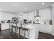 Modern kitchen featuring white cabinets, stainless steel appliances, a large island, and stylish barstool seating at 105 Smoky Emerald Way, Holly Springs, NC 27540