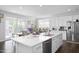 Bright kitchen with white cabinetry, a large island, stainless steel appliances, and adjacent access to the backyard deck at 105 Smoky Emerald Way, Holly Springs, NC 27540