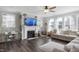 Inviting living room with hardwood floors, a fireplace, ceiling fan and ample natural light from multiple windows at 105 Smoky Emerald Way, Holly Springs, NC 27540