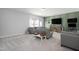 Spacious living room with gray sofas and light green accent wall with large-screen television at 105 Smoky Emerald Way, Holly Springs, NC 27540