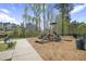 Community playground featuring a slide, climbing structure, and bench seating surrounded by mature trees at 105 Smoky Emerald Way, Holly Springs, NC 27540