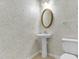 Small powder room featuring pedestal sink, oval mirror and floral wallpaper at 1054 Weathervane Hill Dr, Rocky Mount, NC 27803