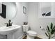 Stylish powder room with a pedestal sink, round mirror, and a window for natural light at 109 Broadwater Dr, Wake Forest, NC 27587
