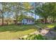 Charming blue outbuilding in a lush backyard, featuring red trim and a well-maintained garden setting at 1108 Friendly Rd, Dunn, NC 28334