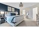 A bright bedroom with a king bed, blue accent wall, modern lighting, and a glimpse into the ensuite bathroom at 1113 Colonial Club Road Rd, Wake Forest, NC 27587