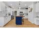 Modern kitchen features white cabinetry, a navy island with seating, stainless steel appliances, and hardwood flooring at 1113 Colonial Club Road Rd, Wake Forest, NC 27587