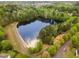 Aerial view of the neighborhood shows homes nestled amongst mature trees and a large pond at 112 Mendells Dr, Holly Springs, NC 27540
