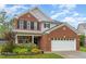Charming two-story brick home with a well-maintained lawn, attached two car garage, and manicured landscaping at 112 Mendells Dr, Holly Springs, NC 27540