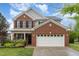 Traditional brick home boasts a two-car garage and well-manicured landscaping at 112 Mendells Dr, Holly Springs, NC 27540