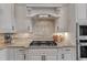 Close-up of a kitchen with a granite countertop, gas range, and decorative white range hood at 116 Palermo Ct, Apex, NC 27539
