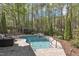 Beautiful inground pool with a rock waterfall feature and a stone patio surrounded by trees at 116 Palermo Ct, Apex, NC 27539