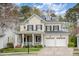 Charming yellow brick two-story home with black shutters, a covered front porch, and an attached two-car garage at 119 Faison Rd, Chapel Hill, NC 27517