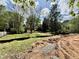 Backyard with exposed dirt awaiting landscaping and yard is surrounded by green trees at 1218 Kingwood Dr, Raleigh, NC 27609