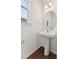 Stylish powder room featuring a pedestal sink, round mirror, and natural light from a window at 1427 Goldsboro Ave, Sanford, NC 27330