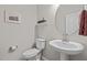 Powder room featuring a pedestal sink, round mirror, and neutral wall paint at 1726 Wimberly Rd, Apex, NC 27523