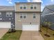 Rear view of modern townhome with garage, tidy lawn, and neat landscaping at 1726 Wimberly Rd, Apex, NC 27523