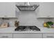 Modern kitchen with stainless steel hood, gas cooktop, white cabinets, and subway tile backsplash at 1726 Wimberly Rd, Apex, NC 27523