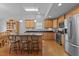 Open kitchen with stainless steel appliances, breakfast bar, hardwood floors, and light wood cabinets at 1728 Fern Hollow Trl, Wake Forest, NC 27587
