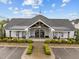 Exterior view of the clubhouse featuring a covered entrance, well-manicured landscaping, and ample parking at 1915 Kings Knot Ct, Apex, NC 27502