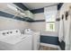 Functional laundry room equipped with a washing machine, dryer, storage shelves, and a window at 202 Faith Ave, Sanford, NC 27330