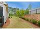 Beautiful backyard showcasing a stone retaining wall, lush greenery, and a fenced perimeter at 2112 Bradford Mill Ct, Apex, NC 27539