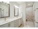 Bright bathroom with double vanity, framed mirrors, and an accessible walk-in tiled shower at 2112 Bradford Mill Ct, Apex, NC 27539