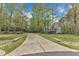 Long concrete driveway leading to a two-story house surrounded by lush, mature trees at 250 Highview Dr, Youngsville, NC 27596