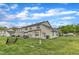 View of the backyard featuring a lawn area and the exterior of townhomes with neutral siding under a partly cloudy sky at 345 Red Elm Dr, Durham, NC 27713