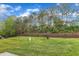 Spacious backyard featuring a lush lawn, a stone retaining wall, and a treeline for privacy at 345 Red Elm Dr, Durham, NC 27713