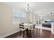 A dining room featuring hardwood floors, a modern chandelier, a window with blinds, and a view into the living room at 4008 Sykes St, Cary, NC 27519
