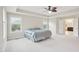 A large main bedroom with a tray ceiling, carpet, a ceiling fan, and an open doorway leading to the main bathroom at 4008 Sykes St, Cary, NC 27519