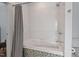 This is a bathtub and shower combination featuring a mosaic tiled base and gray shower curtain at 417 Westbury Dr, Chapel Hill, NC 27516