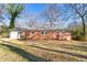 Exterior rear view of a single-story brick home with mature trees and a spacious yard at 5013 Green Oak Dr, Durham, NC 27712