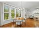 Bright dining area features a modern chandelier, wood floors, and large windows overlooking the lush landscape at 5109 Windance Pl, Holly Springs, NC 27540