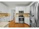 Bright kitchen with white cabinets, stainless steel appliances, granite countertops, and hardwood floors at 5109 Windance Pl, Holly Springs, NC 27540