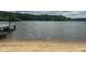 Scenic lake view featuring a sandy beach and a private dock with a boat visible on the water at 5109 Windance Pl, Holly Springs, NC 27540