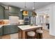 This kitchen features green cabinets, stainless steel appliances, a white countertop island, and pendant lighting at 540 Folk Song Way, Wendell, NC 27591