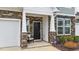 Cozy front porch with stone accents, a black front door, and an ADT security system at 53 Whitley Ridge Dr, Clayton, NC 27527