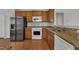 Kitchen featuring granite countertops, wooden cabinets, stainless steel appliances, and hardwood floors for style at 563 Tomkins Loop, Cary, NC 27519