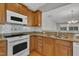 Kitchen with wooden cabinets, granite countertops, white appliances, and tiled backsplash with stainless steel sink at 563 Tomkins Loop, Cary, NC 27519