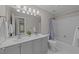 Well-lit bathroom with double vanity, tile backsplash, and bathtub with shower at 5816 Sand Pebble Pl, Raleigh, NC 27613