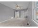 Spacious bedroom with neutral color palette, large windows, and ceiling fan at 5816 Sand Pebble Pl, Raleigh, NC 27613