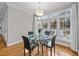 Bright dining area features a glass table, modern lighting, and a wall of windows with backyard view at 5816 Sand Pebble Pl, Raleigh, NC 27613