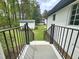 Backyard view from a porch, featuring a shed, white house exterior, black railing, and expansive green lawn at 5920 Holly Dr, Raleigh, NC 27616