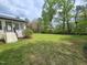 A spacious backyard, featuring a lush lawn, complemented by mature trees and a view of the home's exterior at 5920 Holly Dr, Raleigh, NC 27616