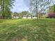 Spacious backyard showcasing a well-manicured lawn, mature trees, outbuilding and home exterior at 5920 Holly Dr, Raleigh, NC 27616